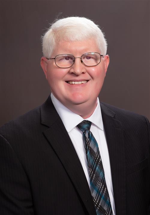 Jonathan Sherbert is smiling and wearing a black pinstripe suit.